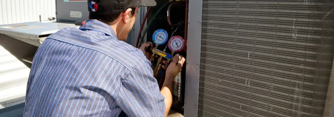 HVAC technician servicing a condenser unit in Omak