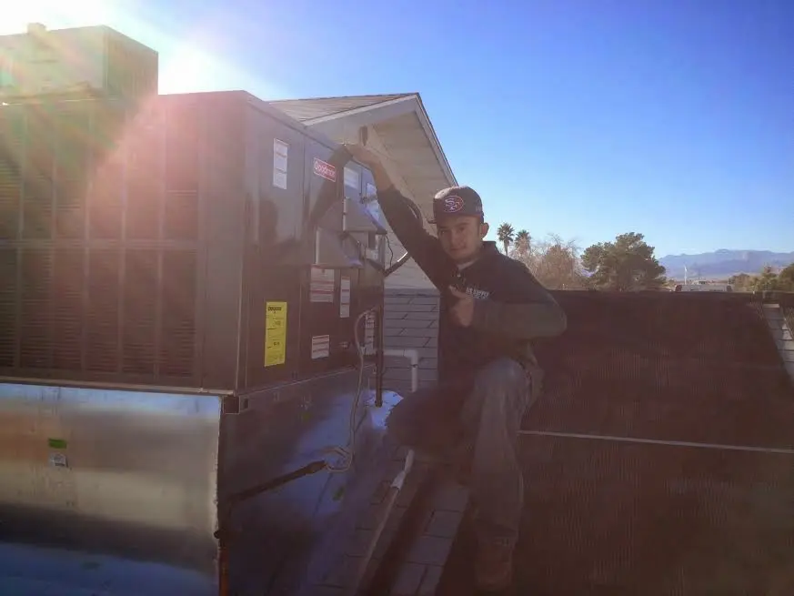 HVAC technician performing Air Duct Cleaning on a rooftop unit in Omak
